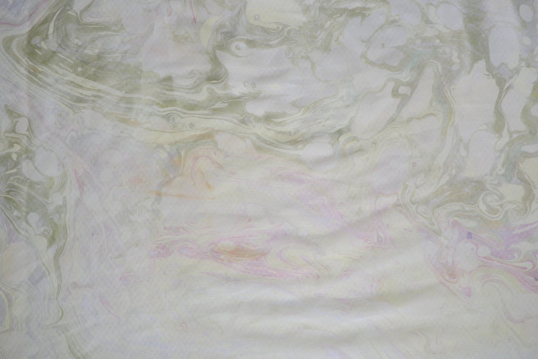 Close-up detail of marbled silk in pale celadon and cream tones