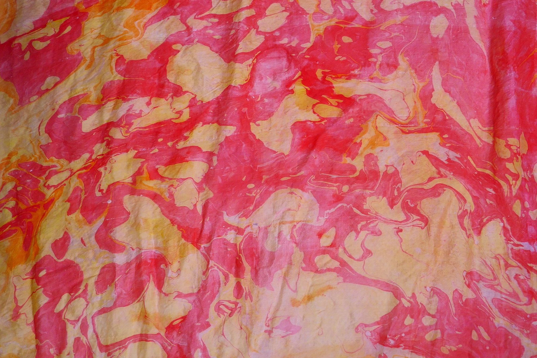 Close-up detail of marbled silk in vivid coral and red stone pattern