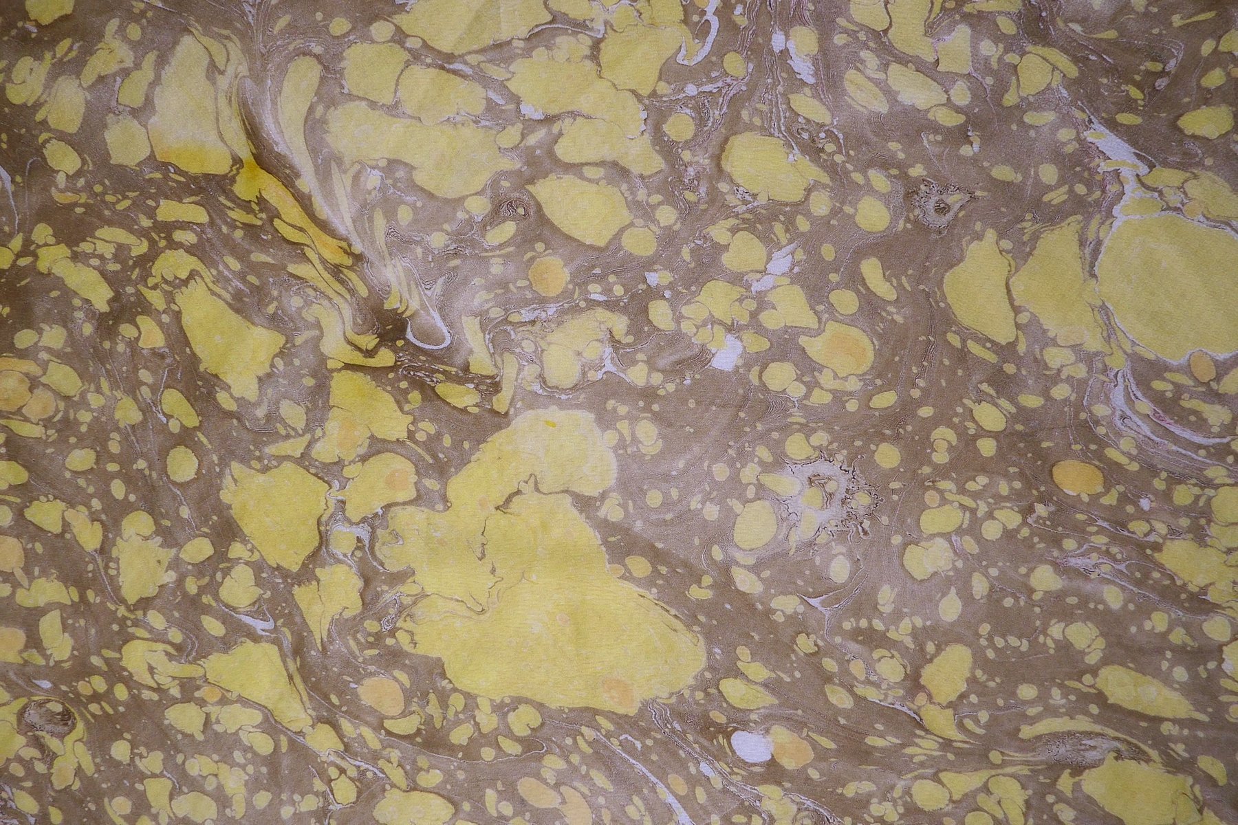 Close-up detail of marbled silk in golden yellow and umber battal pattern