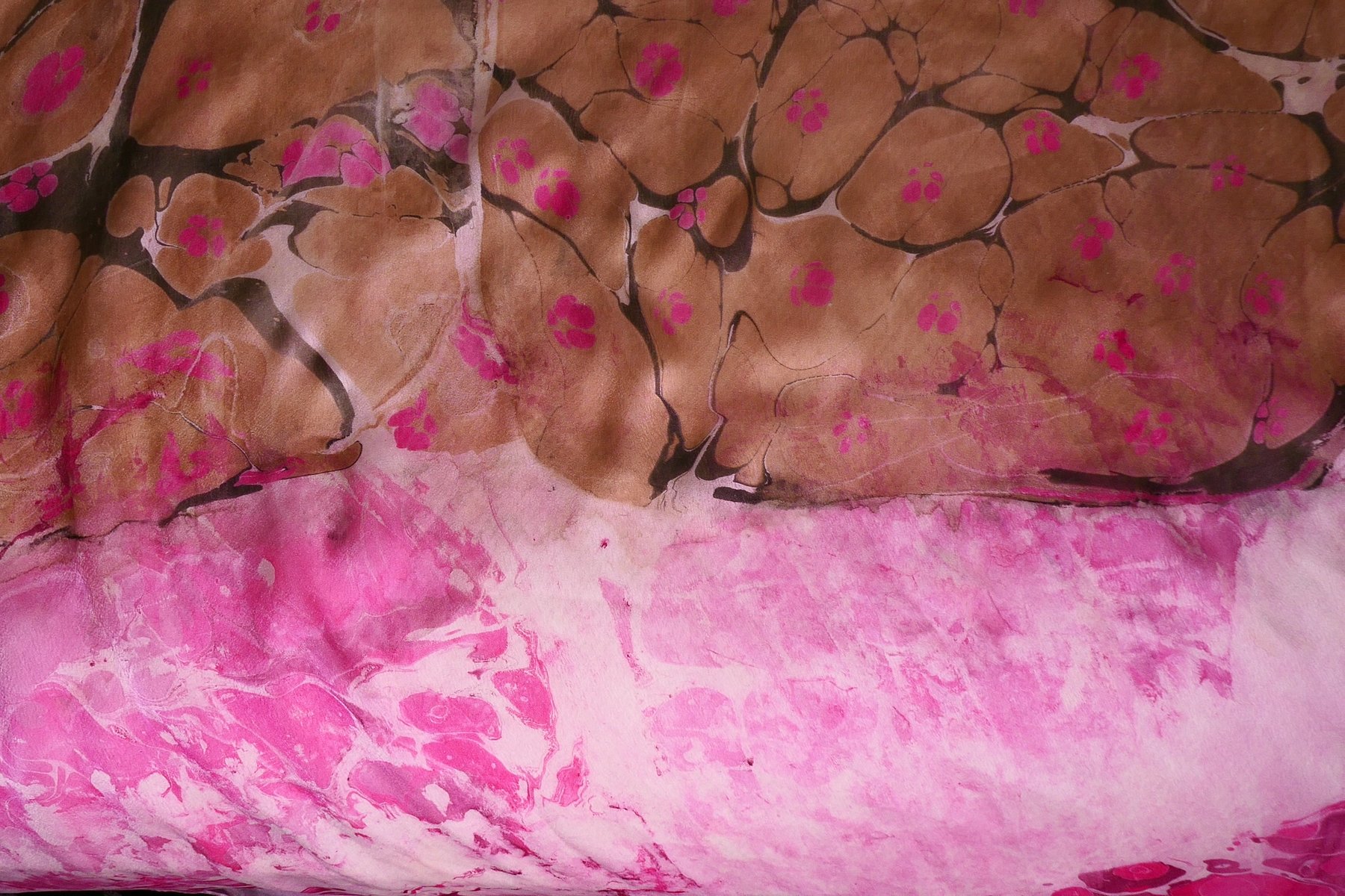 Close-up detail of marbled silk with pink blossoms over brown stone pattern