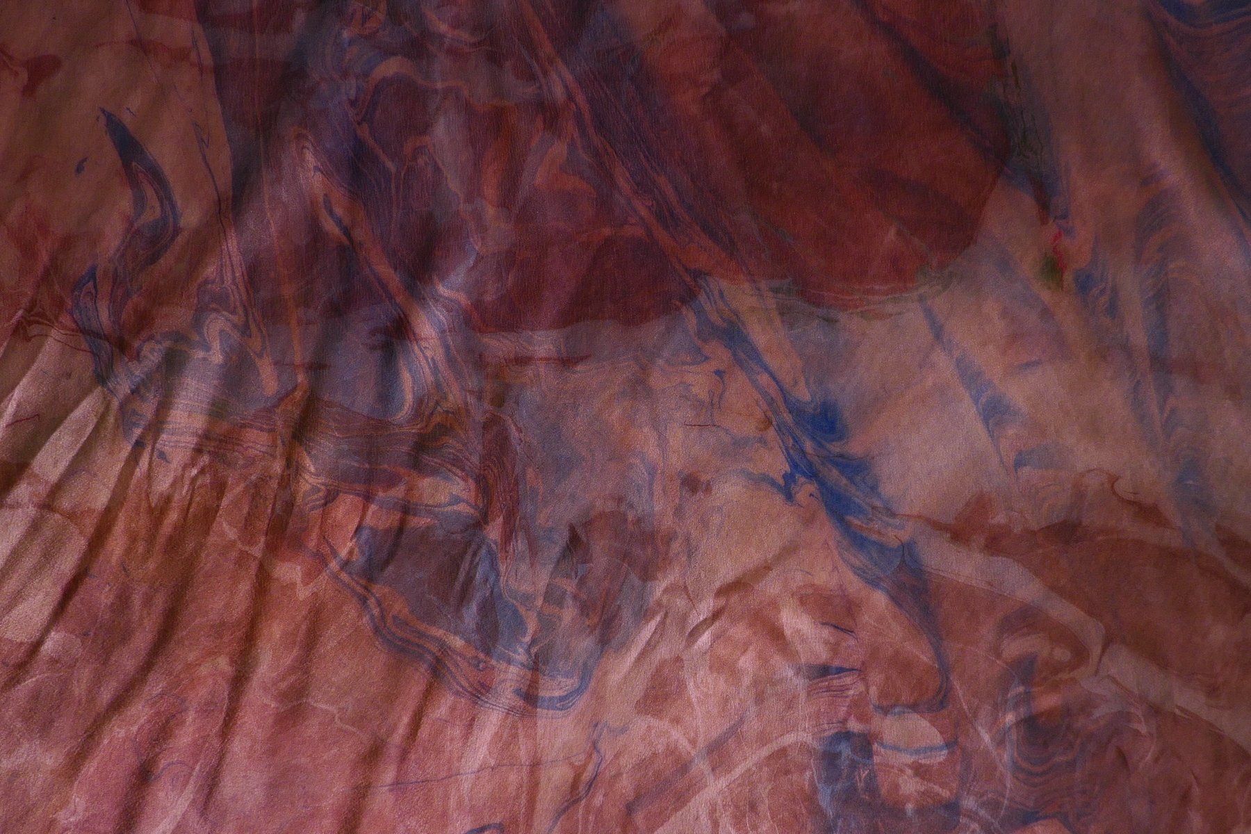 Close-up detail of marbled silk in rust and indigo tones
