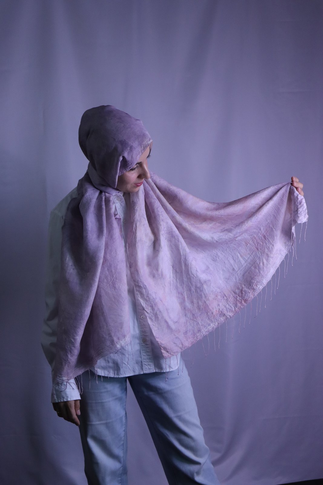 Hand-marbled silk scarf in soft lavender tones, held outspread to show the marbled pattern