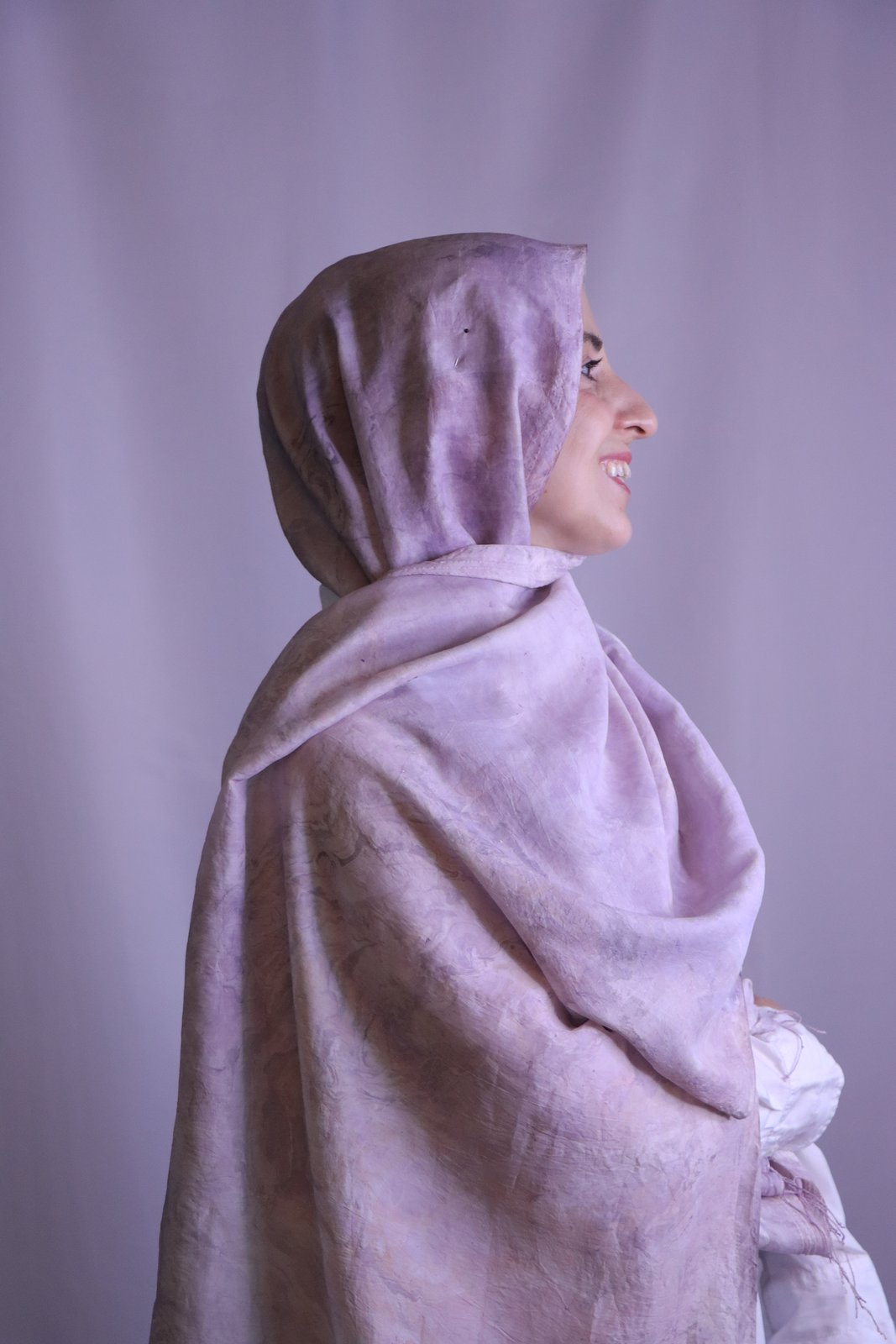 Hand-marbled silk scarf in lavender tones, worn wrapped, photographed in profile