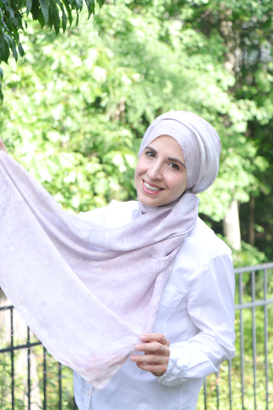 Hand-marbled silk scarf in pale lavender, held up outdoors to catch the light