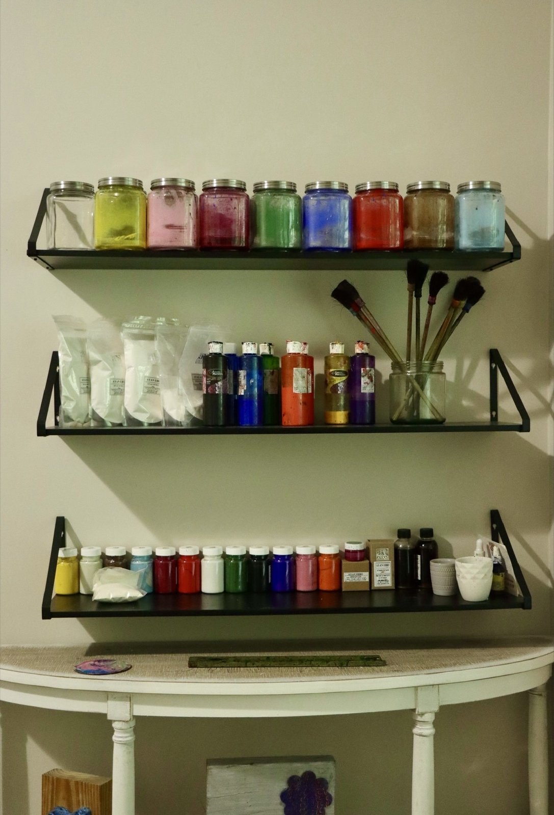 Studio shelves lined with jars of hand-prepared marbling pigments, traditional brushes, and natural materials