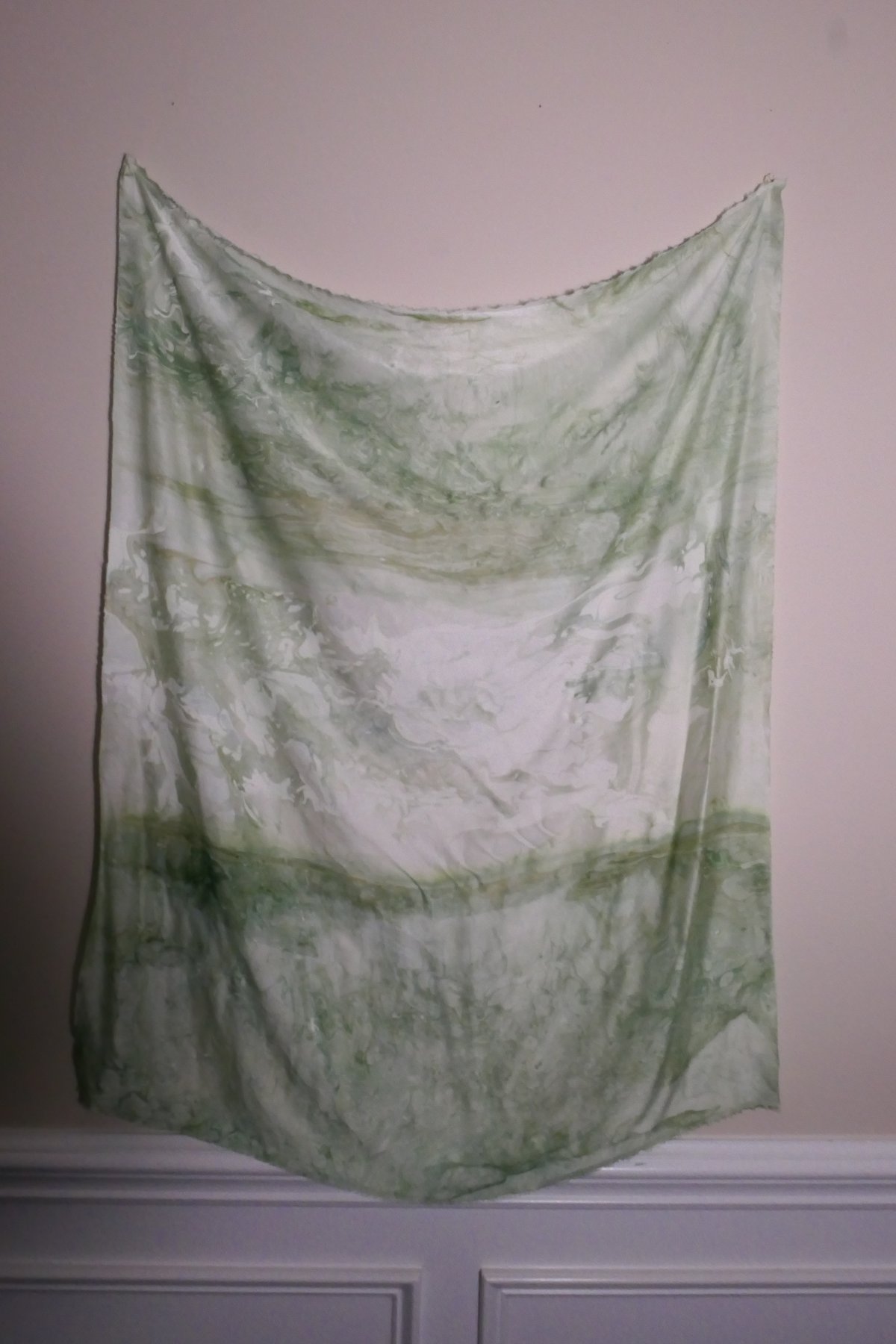 Marbled silk panel in soft greens and white, hung on a wall