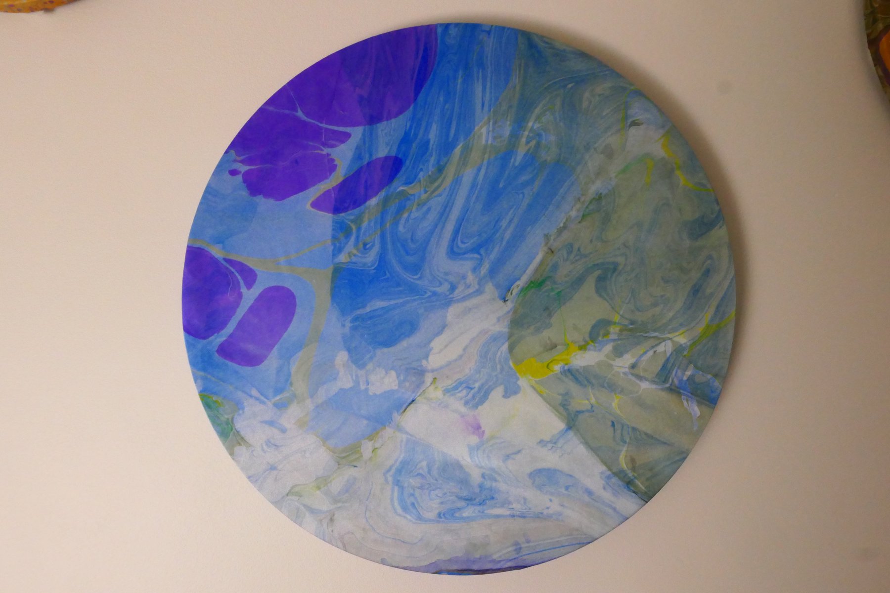 Round marbled wall panel with sweeping blue, white, and violet pattern