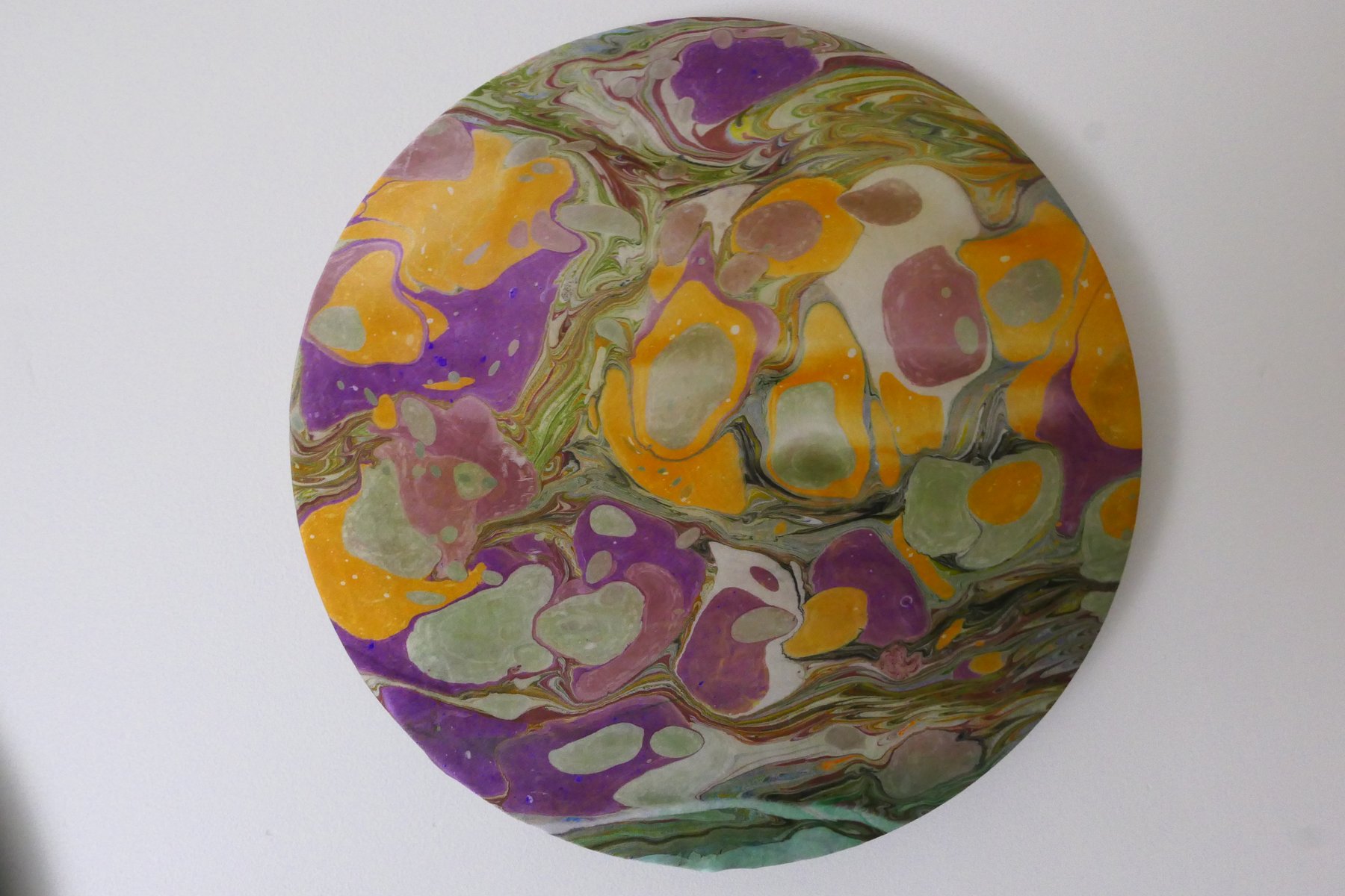 Round marbled wall panel with large stone pattern in violet, gold, and sage green